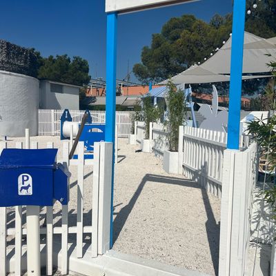 Ein einladender Hundespielplatz mit Parkplatz für Hunde, umgeben von einem weißen Zaun.