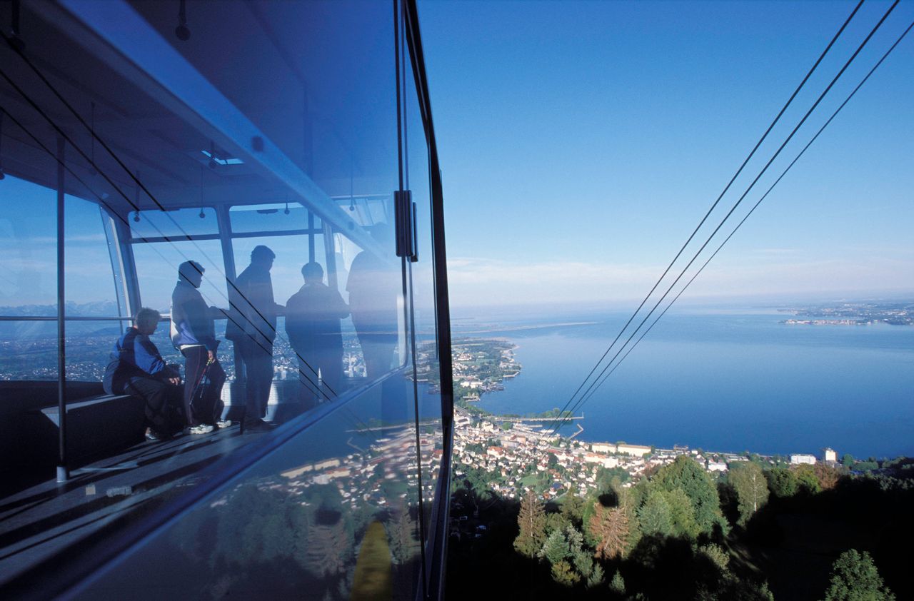 Hund auf Bergbahn: Ausblick über See und Landschaft Hund in Gondel mit Panoramablick auf See und Küstenlandschaft während Bergfahrt
