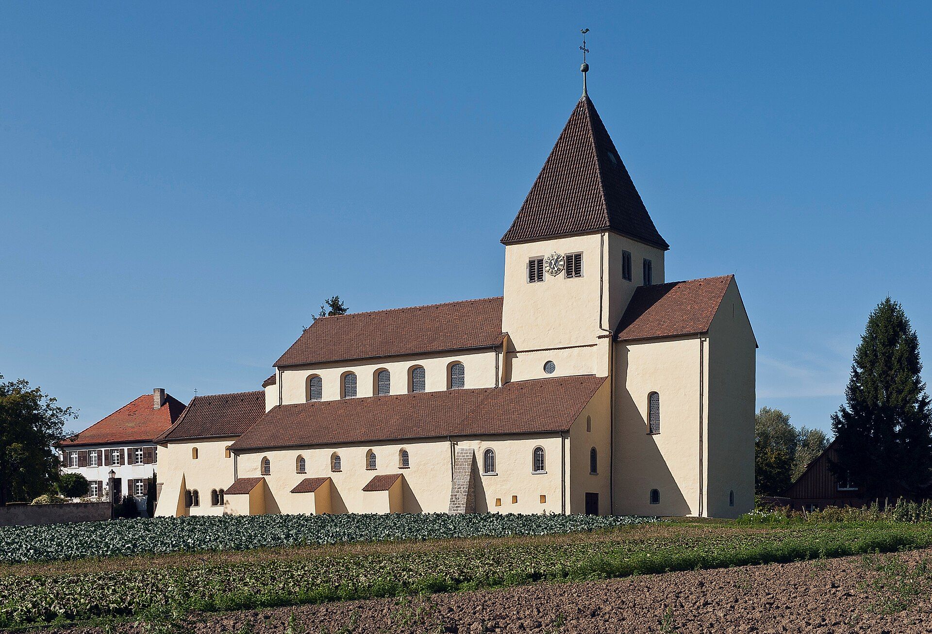Romanische Kirche mit Spitzturm in ländlicher Umgebung, ideal für Hundewanderungen