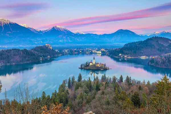 Blick auf den Bleder See mit seiner Insel und den umliegenden Bergen bei Sonnenaufgang.
